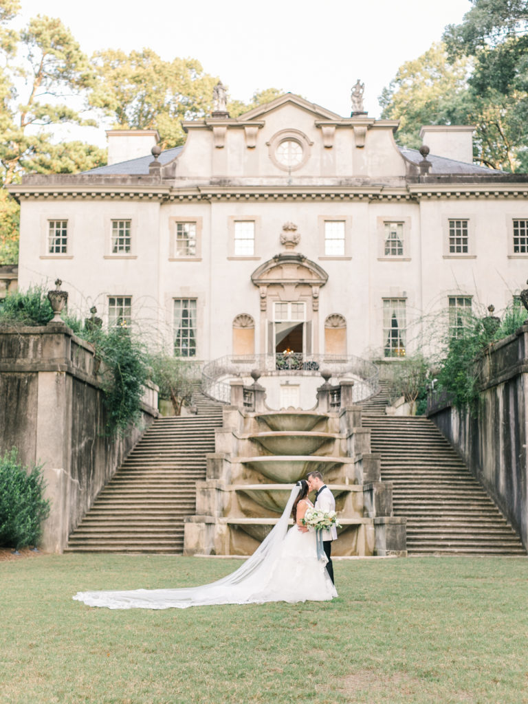 The bride and groom share a kiss outside Swan House.